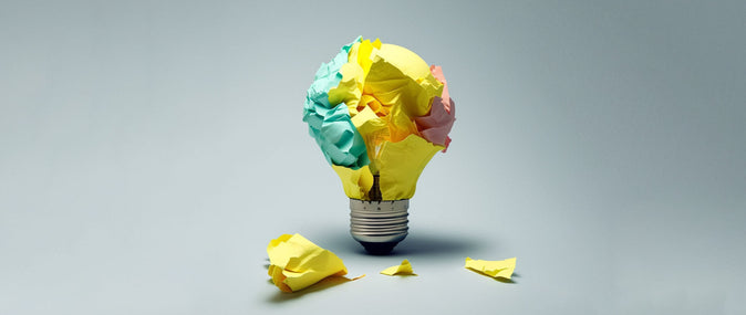 Crumpled colored paper shaped like a lightbulb on a gray background representing passive income ideas.